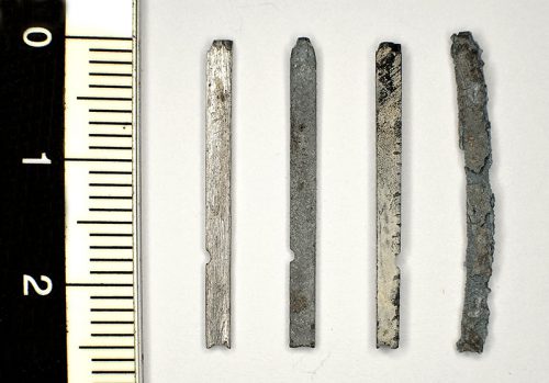 Figure 1. Four types from left to right: without corrosion; with an even dark grey corrosion; with a dense white layer of passive corrosion and finally an example of a vigorously corroded item that has lost all structural rigidity, form and readability.
